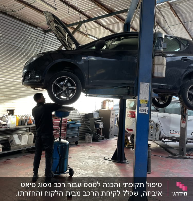 מכונית על ליפט במוסך, מכונאי עובד מתחתיה